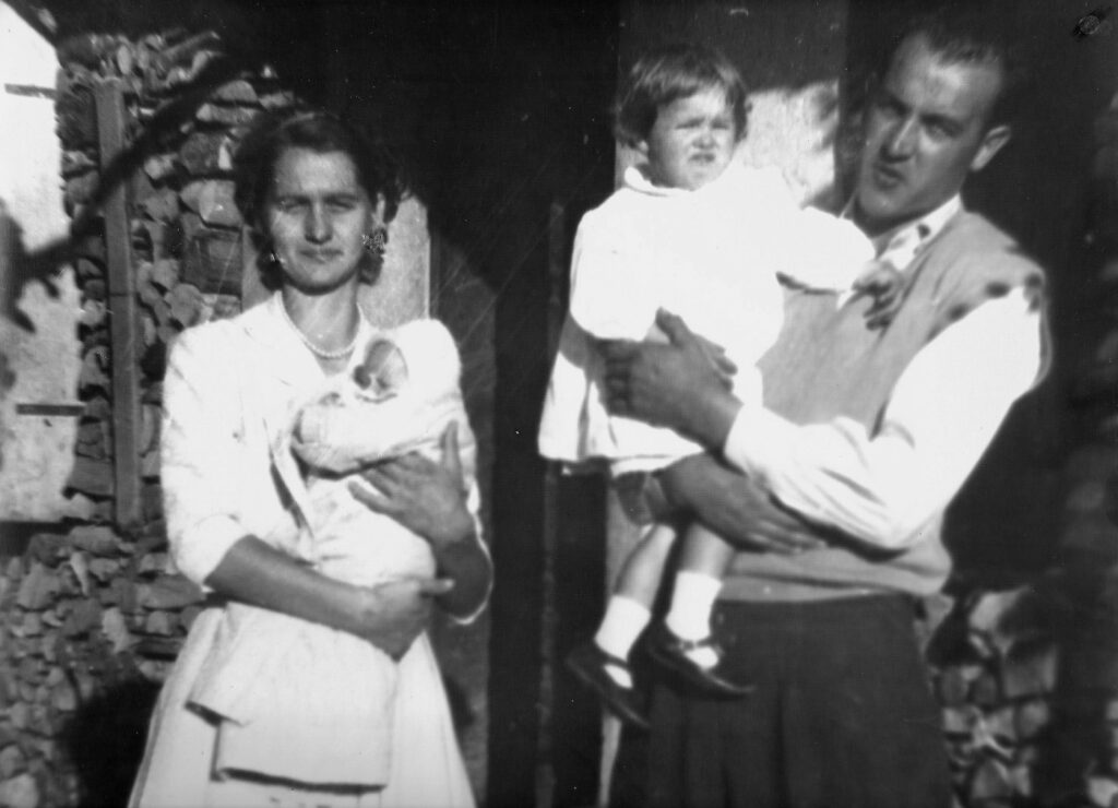 Nella foto, la piccola Marisa è in braccio alla mamma, mentre il papà tiene la sorella Marula; il terzogenito Maurizio verrà alla luce due anni dopo, per poi perire, due anni più tardi, nella tragedia del Vajont assieme ai genitori e alla sorella più grande.